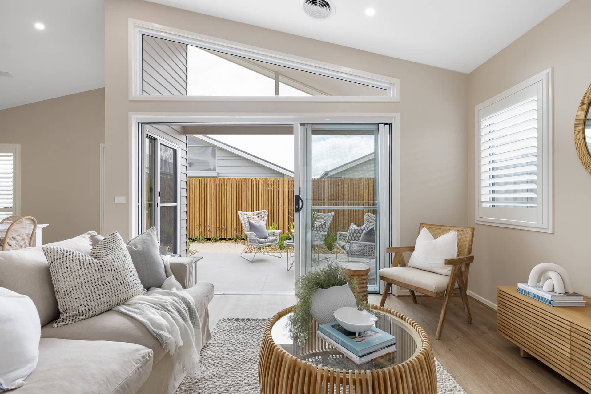 Living room with a sliding glass door opening to a paved outdoor area with outdoor seating.