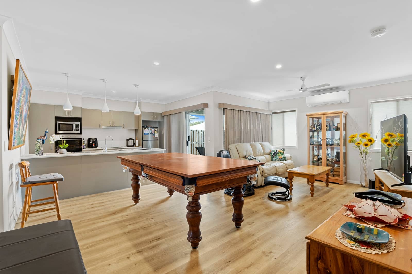 Open-plan living area in an Ingenia Lifestyle home, featuring a kitchen, pool table, sofa, and TV.