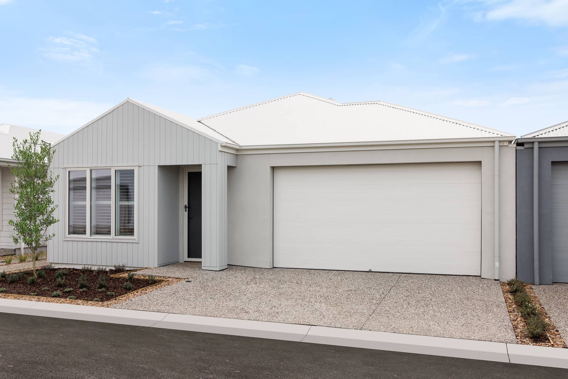 Light grey Ingenia Lifestyle home featuring a white roof, attached garage, and low-maintenance landscaped front garden.