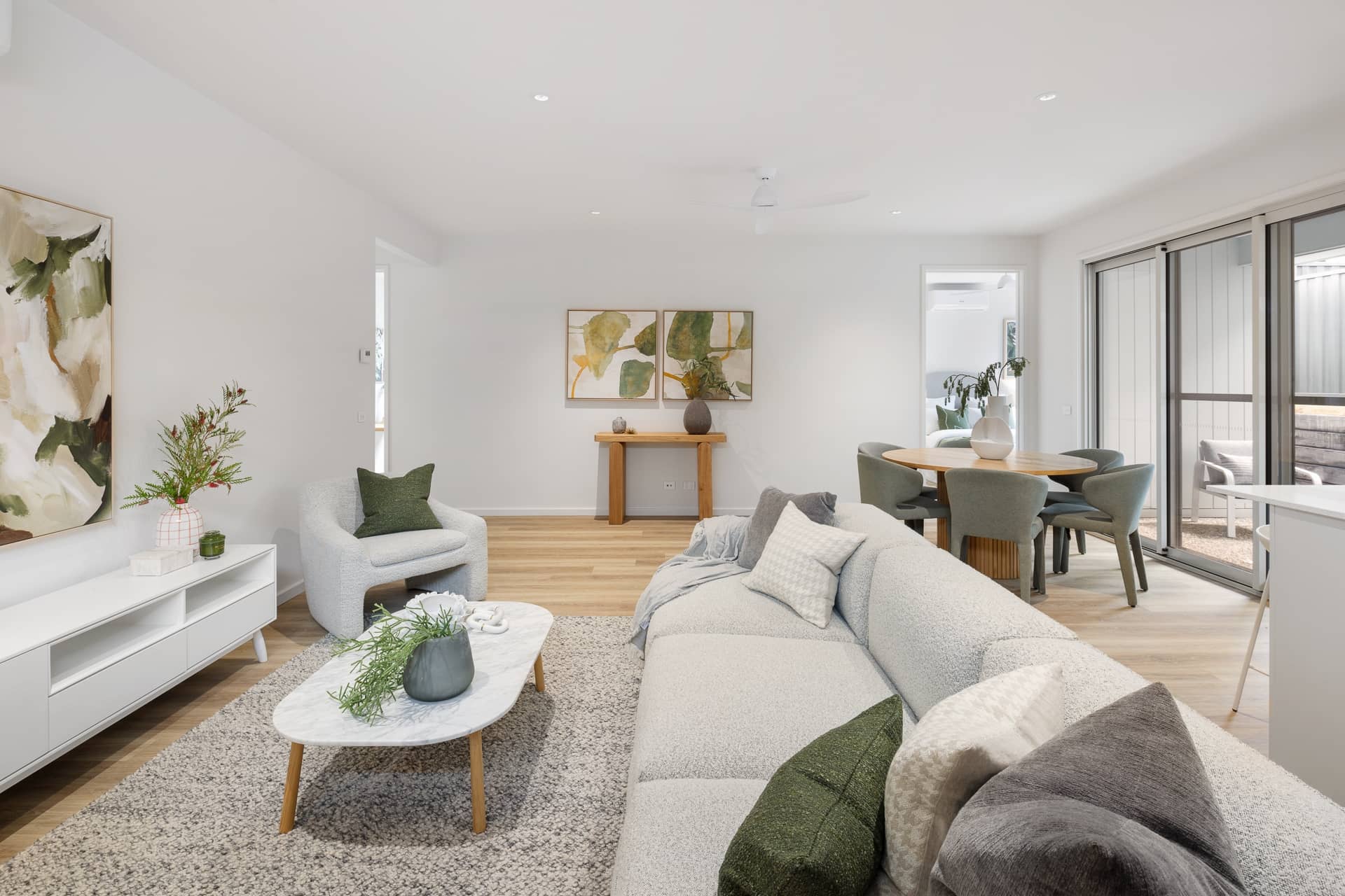 Modern open-plan living and dining area in an Ingenia Lifestyle home with light furniture, timber flooring, and sliding doors.