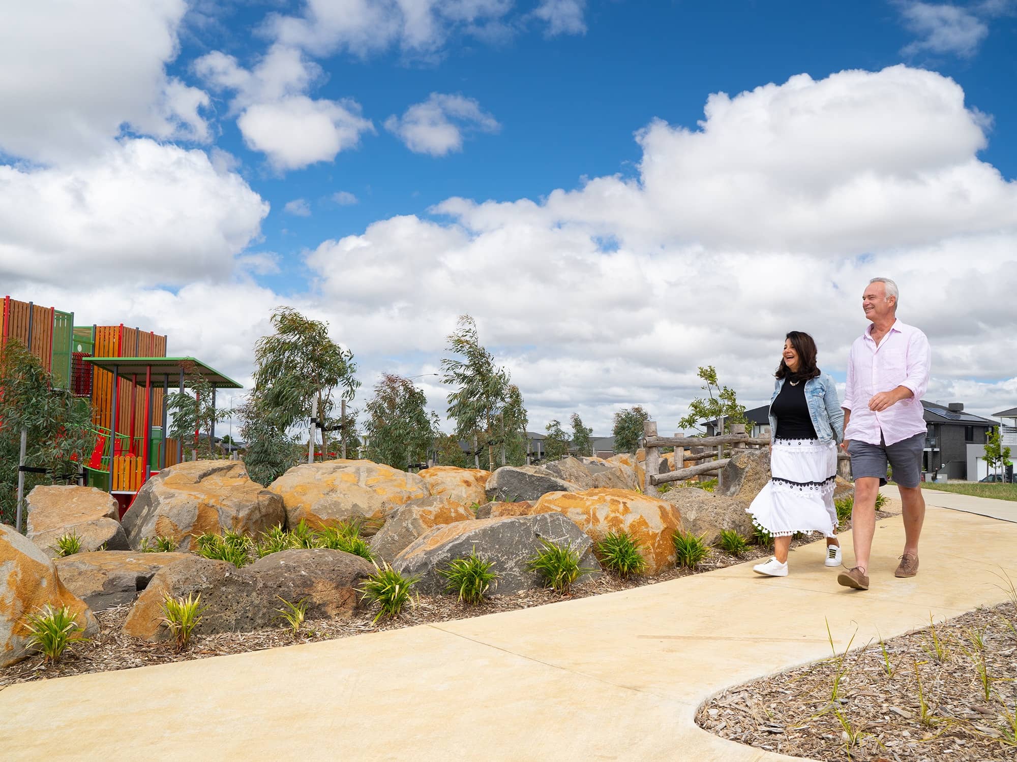 Couple walking on a path in an Ingenia Lifestyle community with natural rock landscaping.