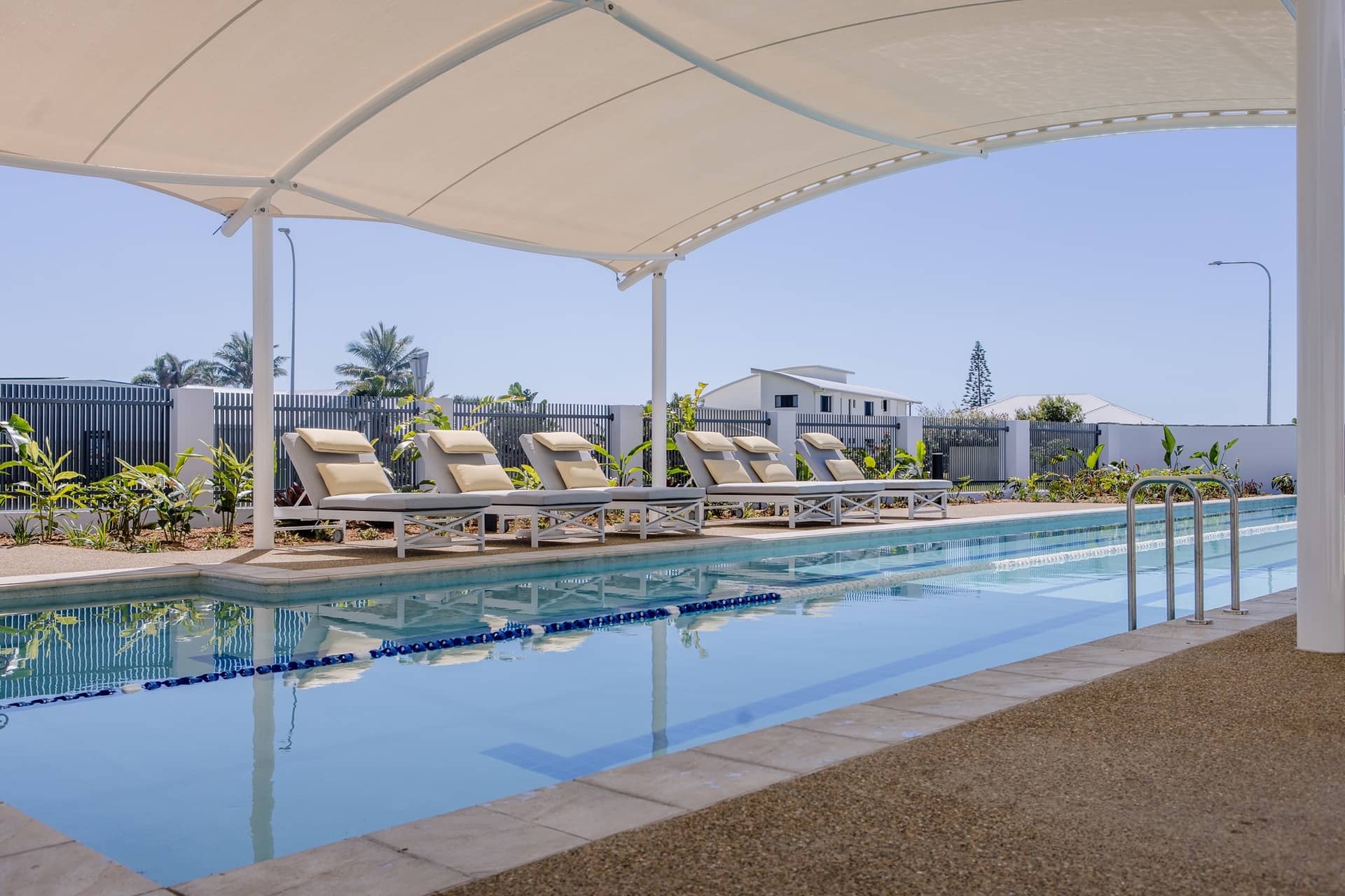 A lap pool is pictured with several loungers shaded by a canopy.