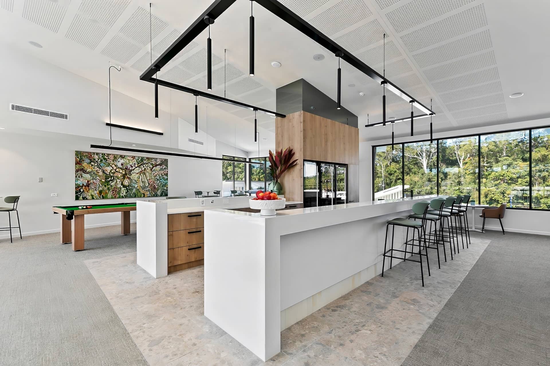 Modern Ingenia Lifestyle community lounge with a bar, pool table, abstract art, and large windows overlooking bushland.