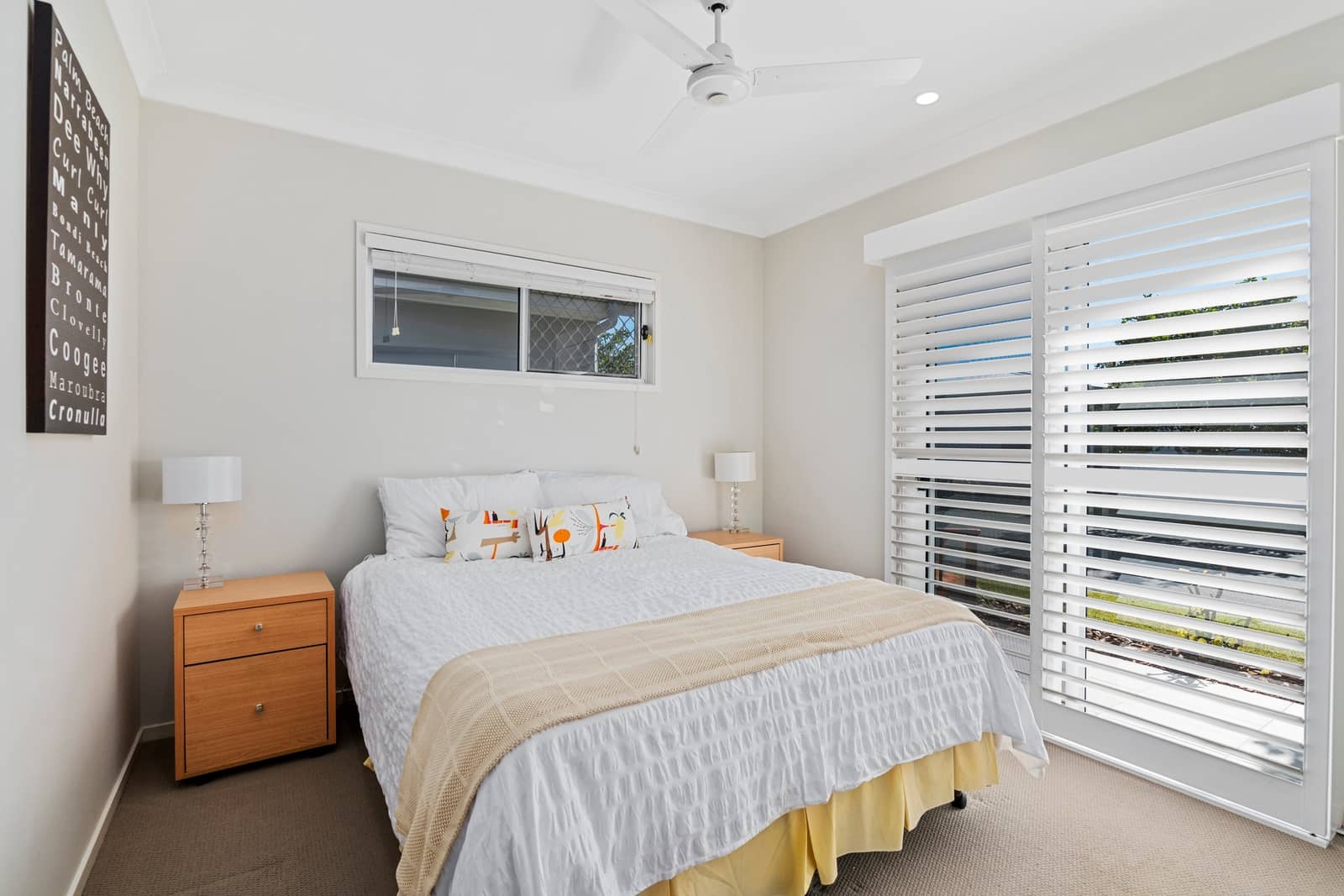 A bright bedroom with a queen-sized bed and a ceiling fan in an Ingenia Lifestyle community.