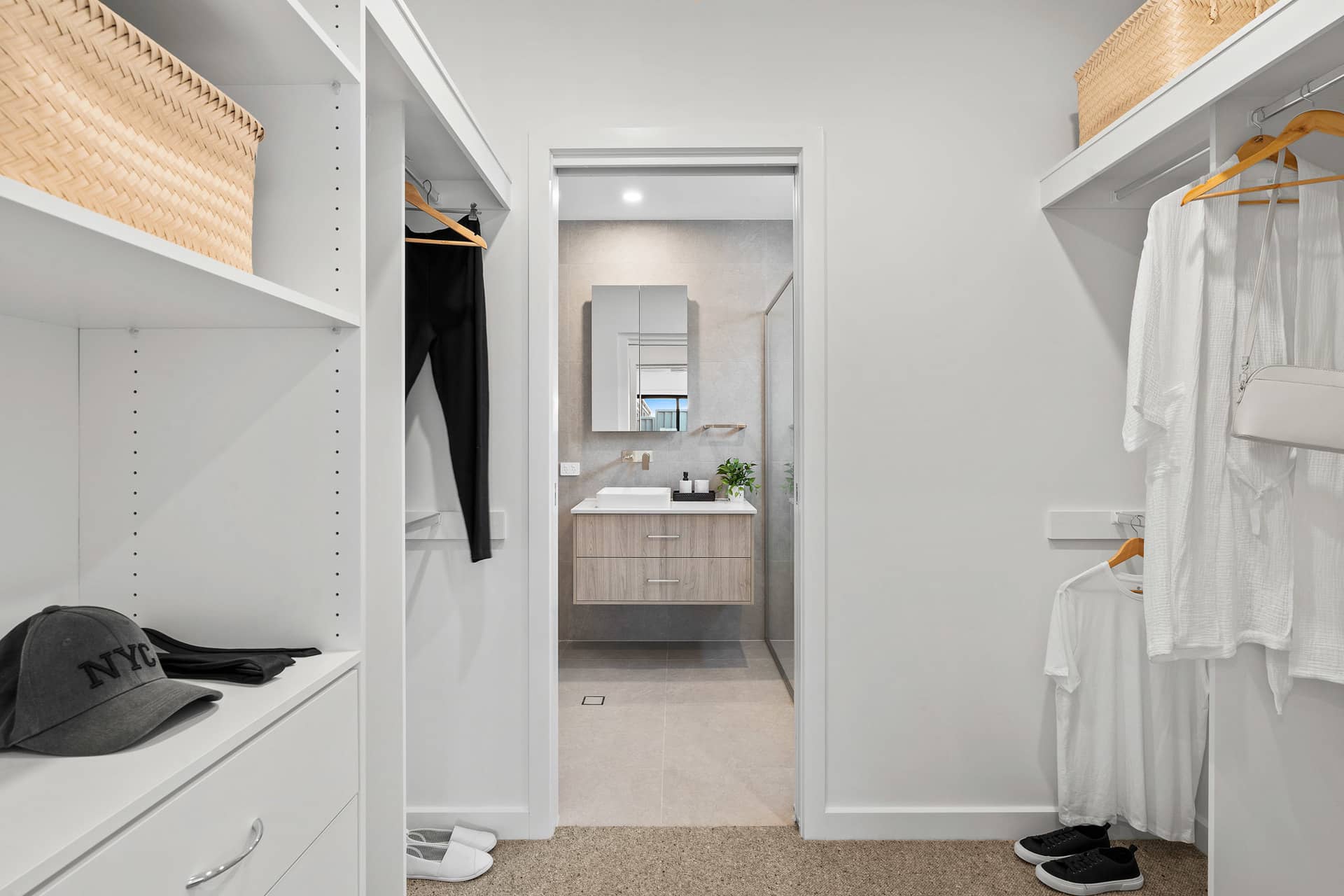 Walk-in wardrobe in an Ingenia Lifestyle over-55 home, featuring white shelving and a view into a modern bathroom.