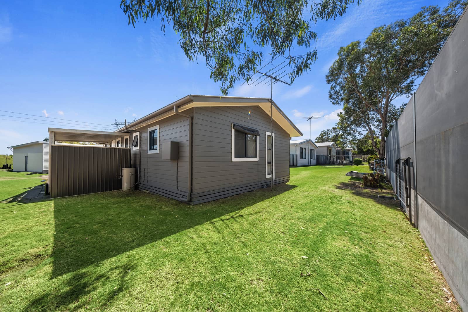 Ingenia Lifestyle community with a grey land lease home and green lawn under a blue sky.