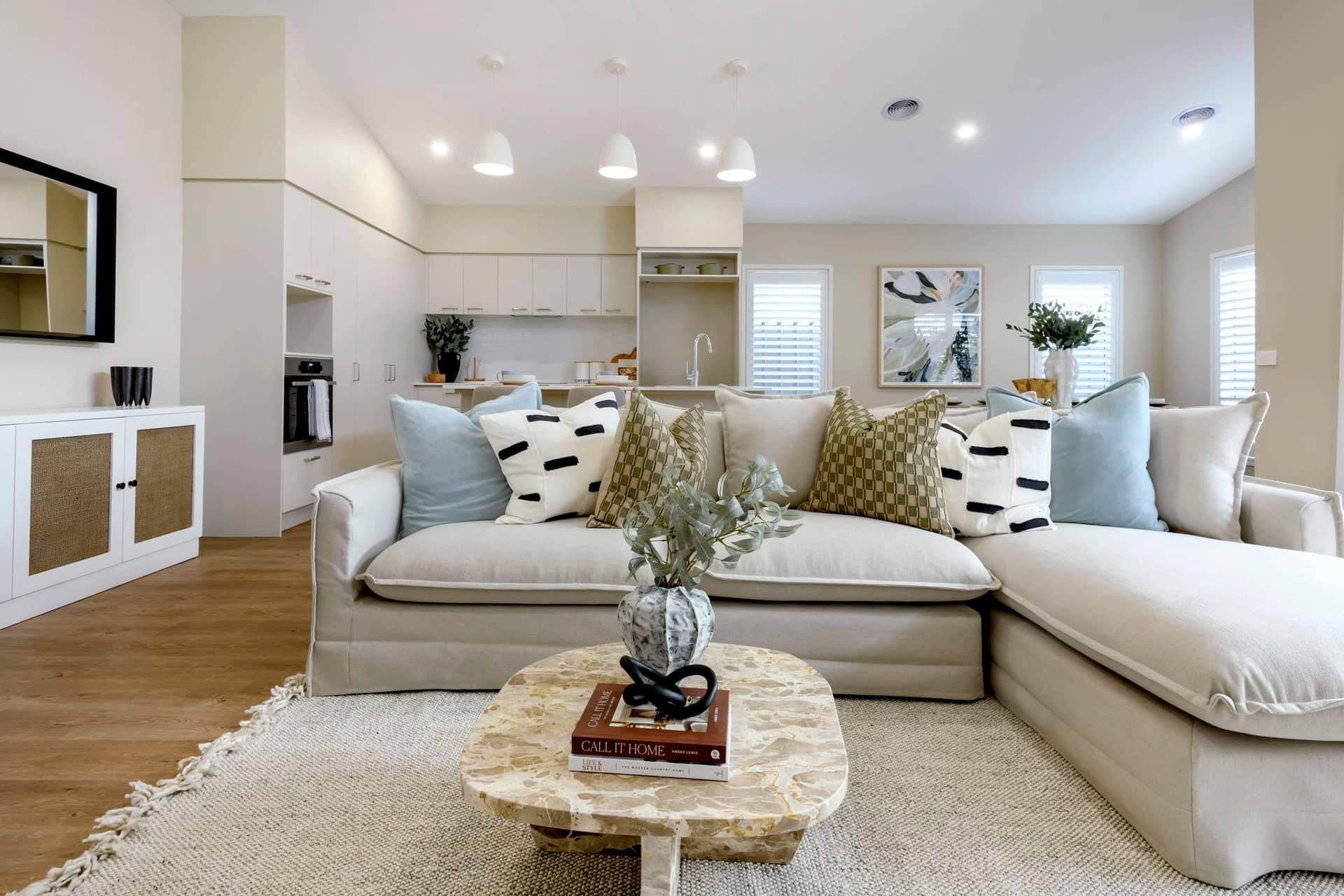 Neutral-toned sectional sofa with decorative pillows in an open-plan living area of an Ingenia Lifestyle community.