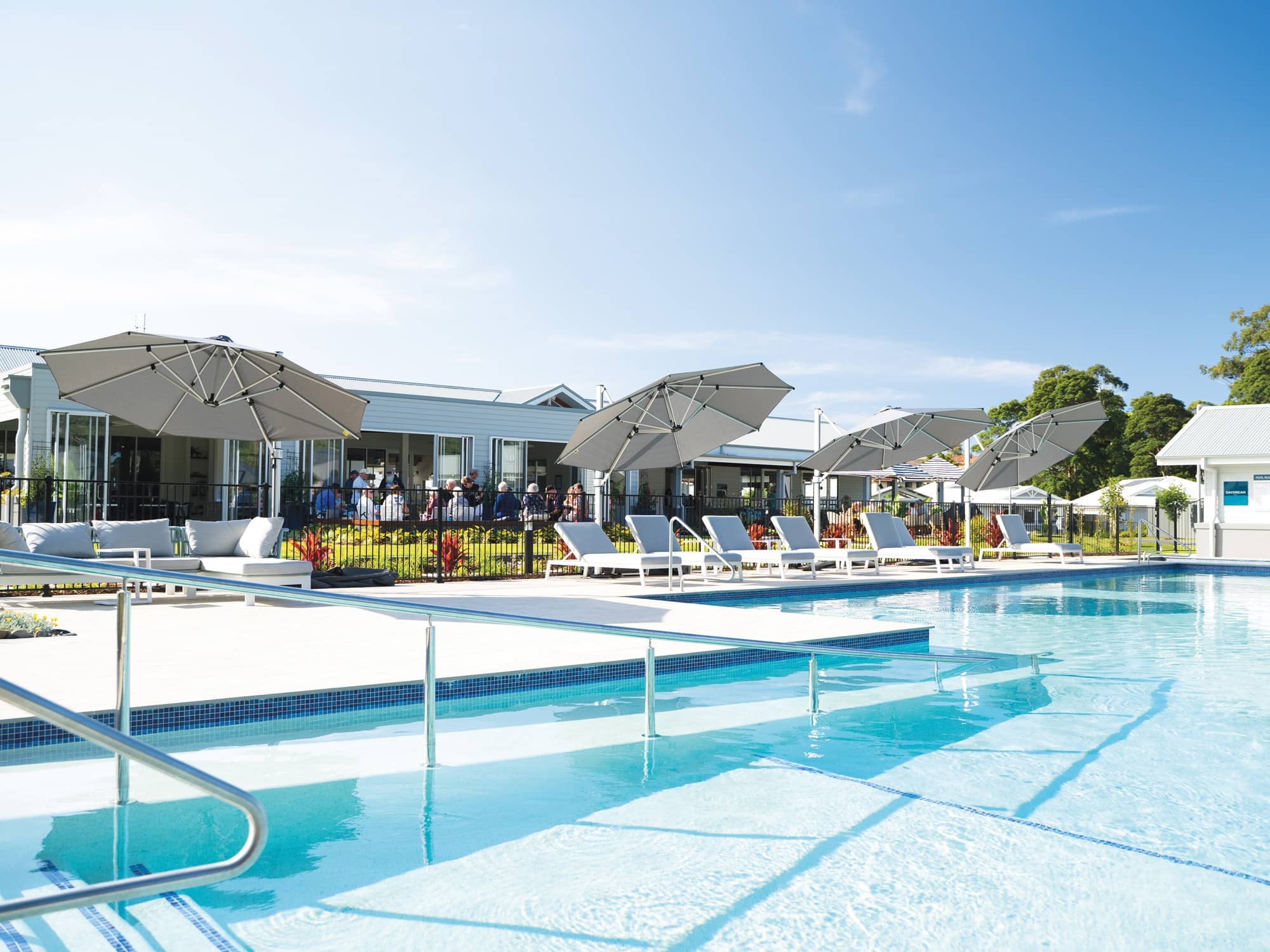 Ingenia Lifestyle community pool with sun loungers and shaded seating areas.