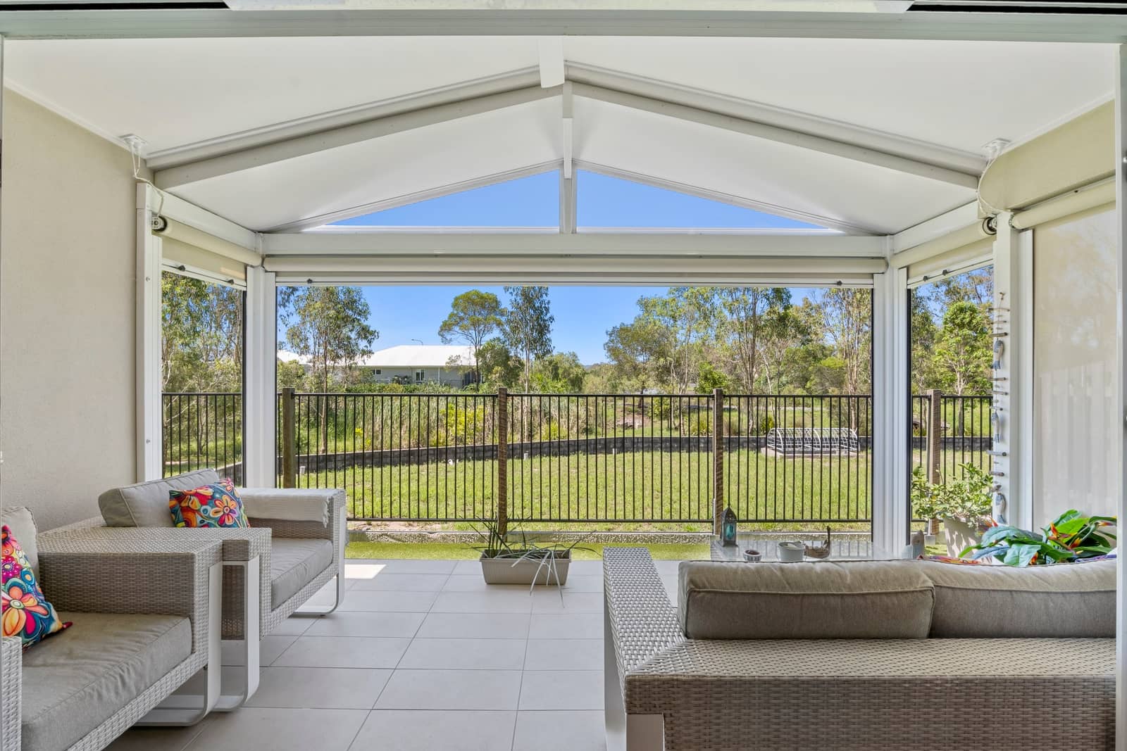 View from an Ingenia Lifestyle community verandah with outdoor seating, overlooking a garden and trees.