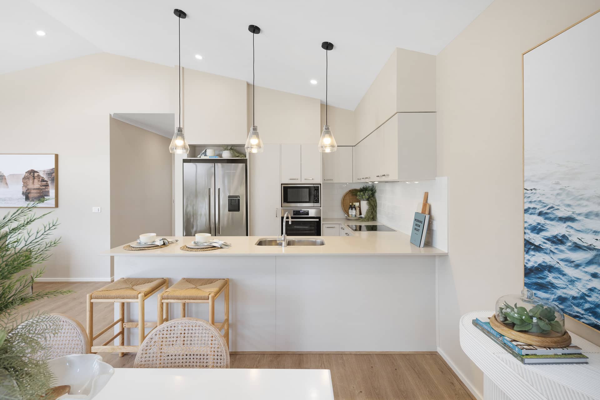 Modern kitchen with stainless steel appliances, light cabinetry, and island with bar stools.