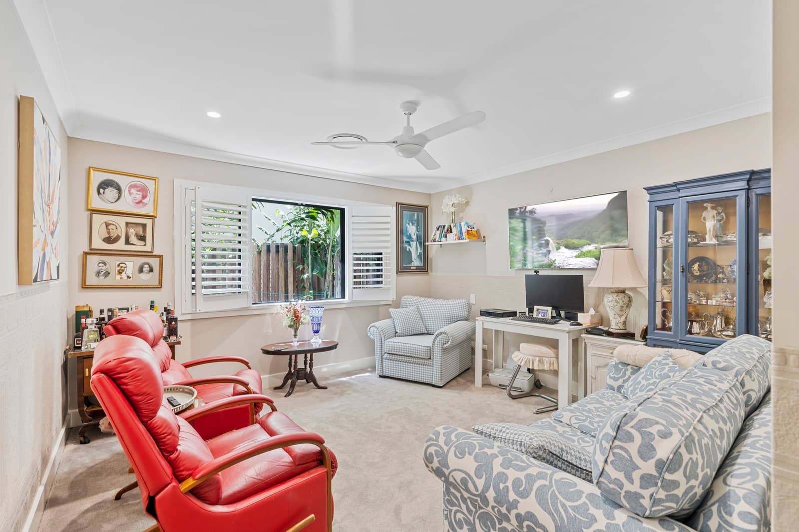 Living room with red leather chairs, a blue patterned sofa, and a window overlooking greenery.