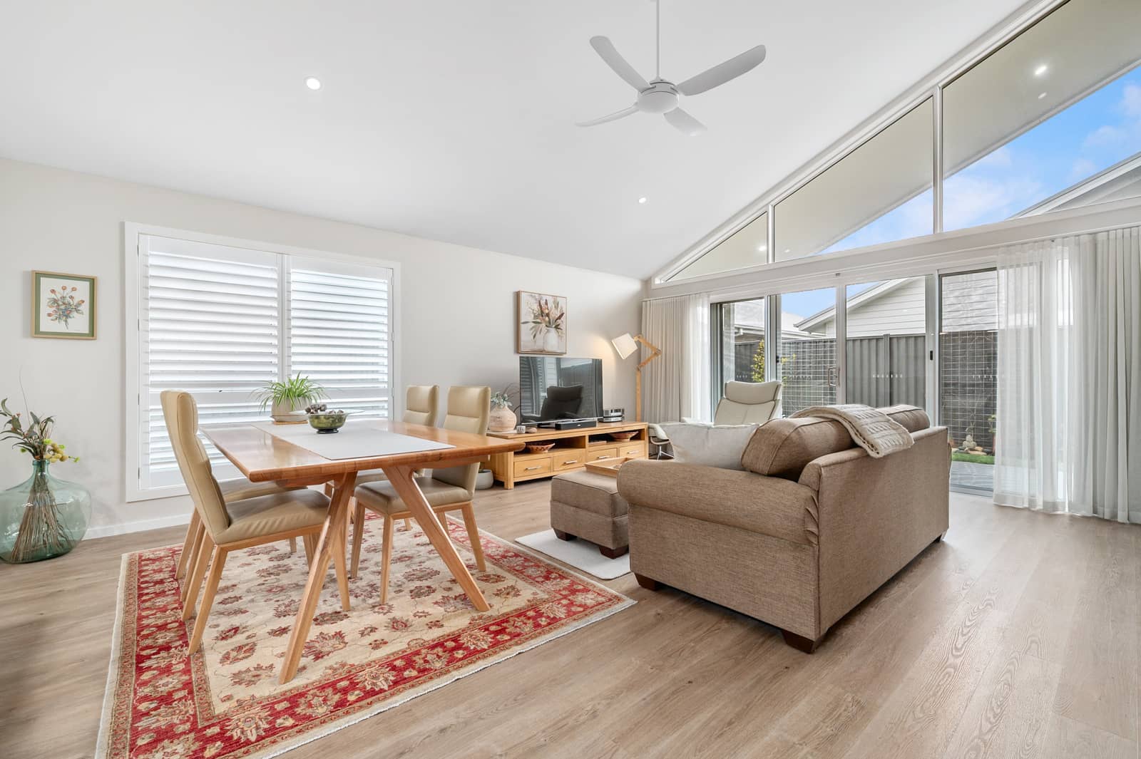 Bright open-plan living and dining area in an Ingenia Lifestyle home, featuring a dining table, sofa, and large windows.