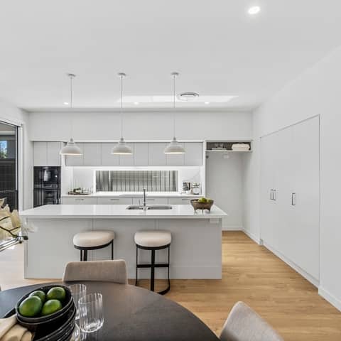 Modern kitchen with a large island, pendant lights, and built-in appliances in an Ingenia Lifestyle community.