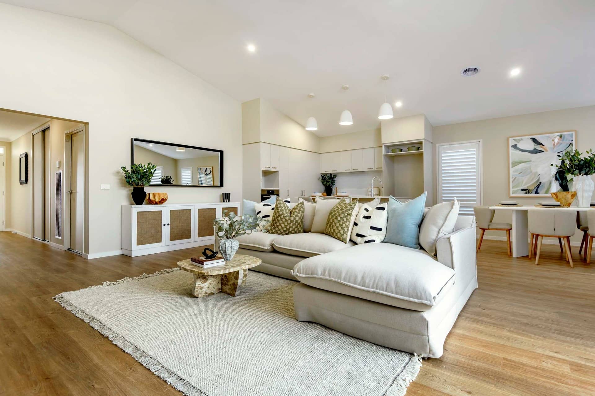 A bright, open-plan living and dining area in an Ingenia Lifestyle community with a large sectional sofa, coffee table, and dining setting.