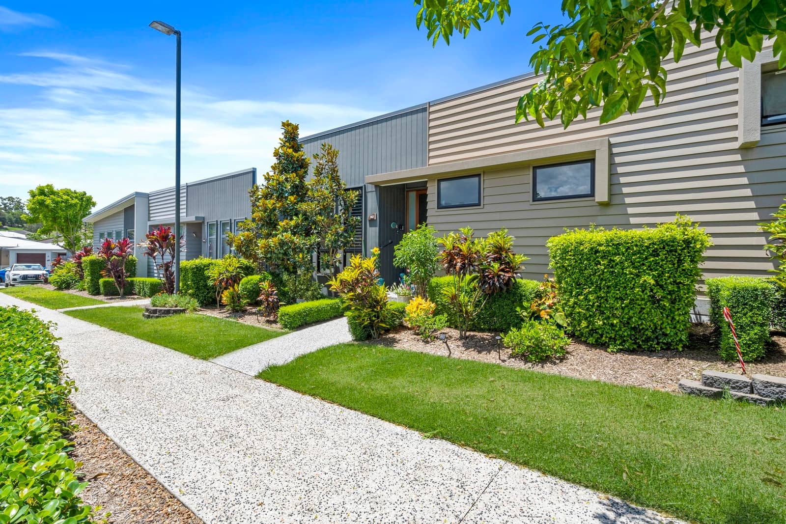 A paved pathway leads through manicured gardens to modern Ingenia Lifestyle homes.