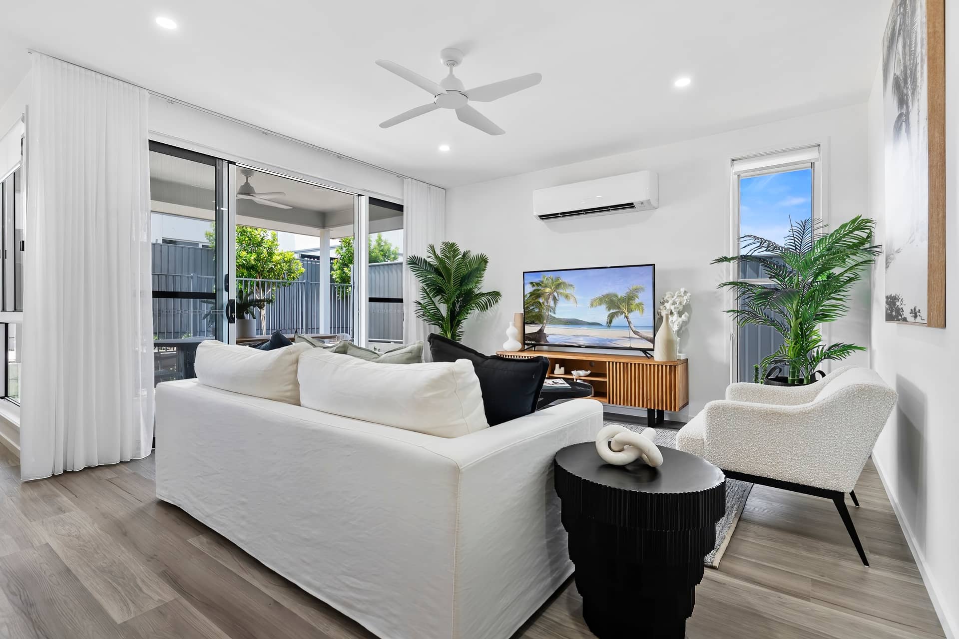 Bright, modern living room in an Ingenia Lifestyle community with a white sofa, textured armchair, and TV.
