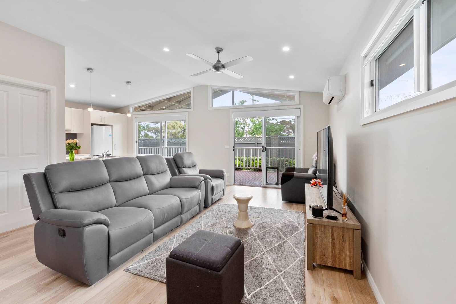Light-filled living room in an Ingenia Lifestyle home, featuring grey sofas, light timber floors, and sliding doors to a deck.
