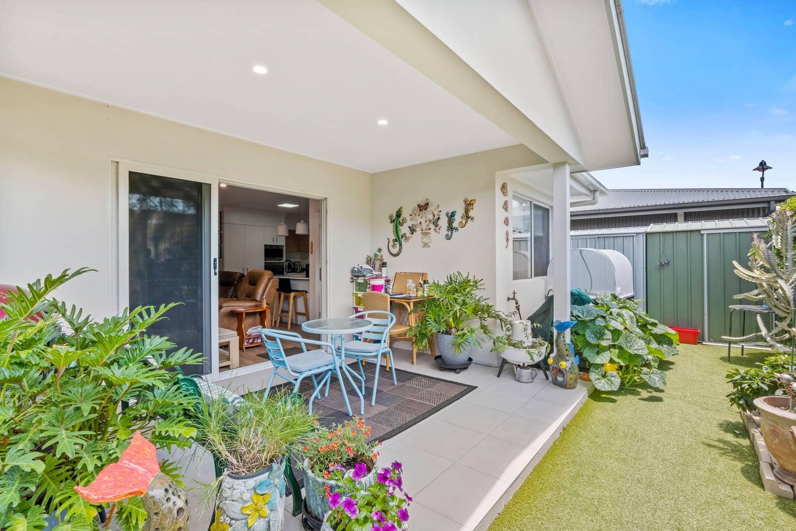 Low-maintenance backyard patio of an Ingenia Lifestyle home with outdoor seating, plants, and faux grass.