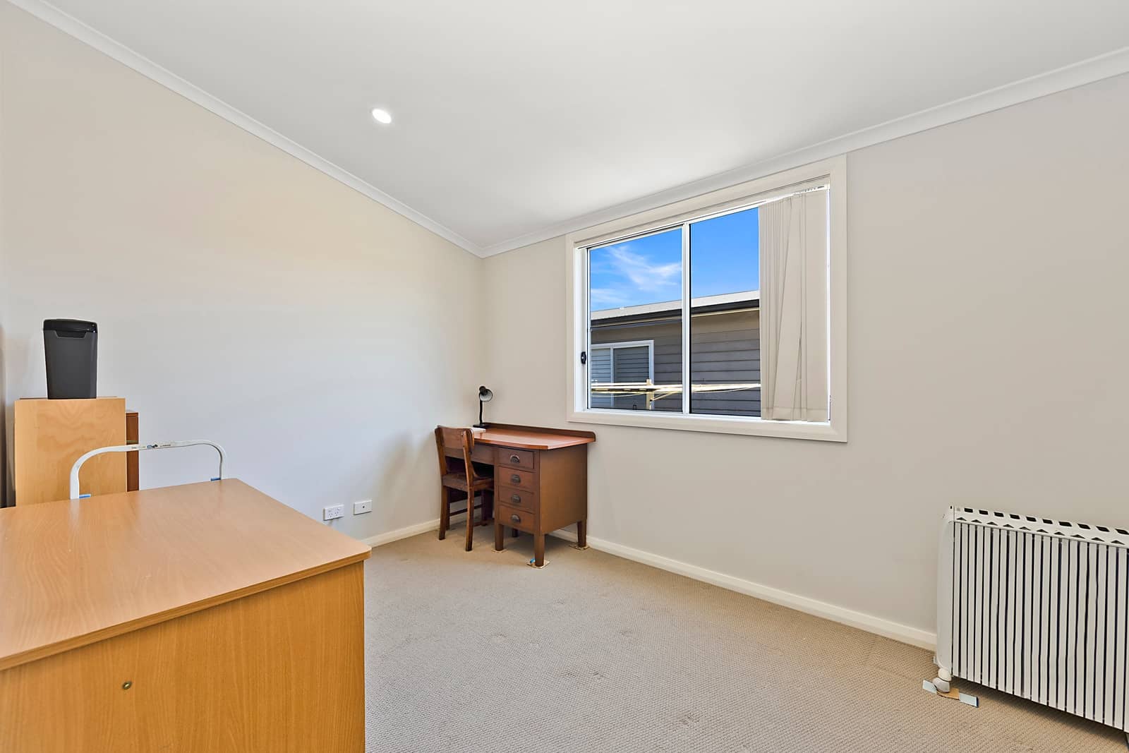 A bright study or spare room in an Ingenia Lifestyle low-maintenance home, with a desk, carpet, and window view.