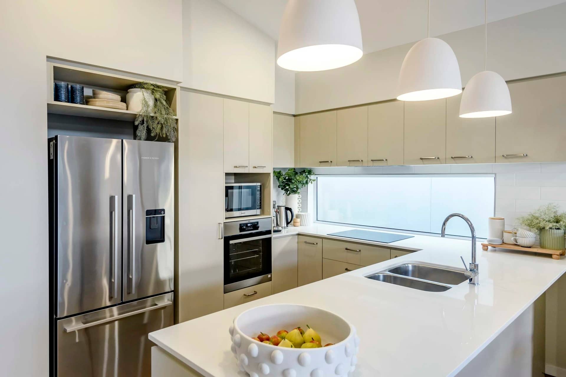 Modern kitchen with stainless steel refrigerator, built-in oven and microwave, and sleek cabinetry.