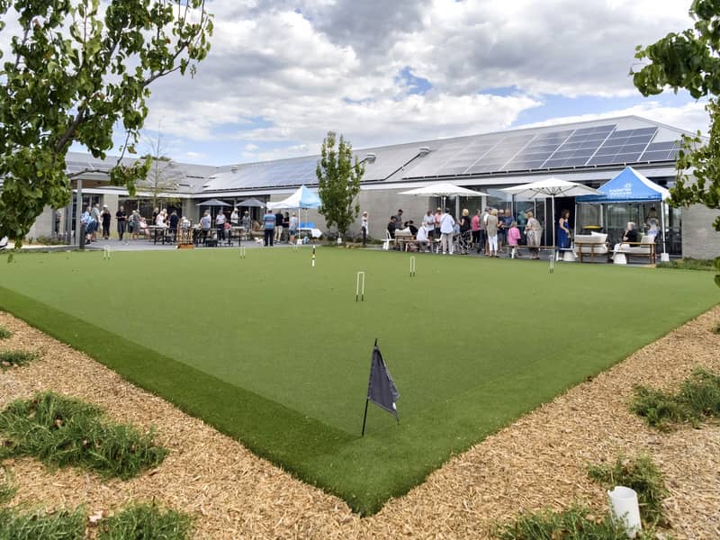 A group of people gather outside a community building with solar panels on the roof.