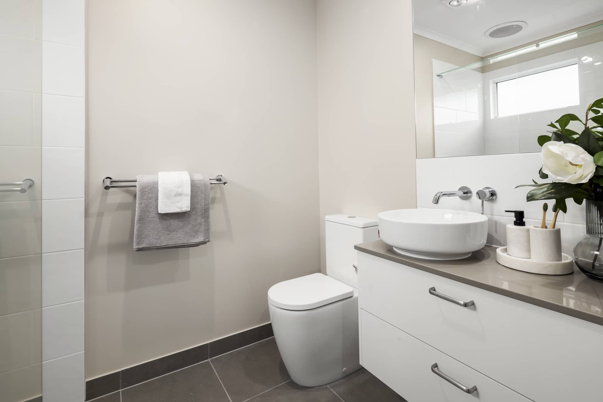 A modern bathroom with a toilet, vanity, and sink in an Ingenia Lifestyle community.
