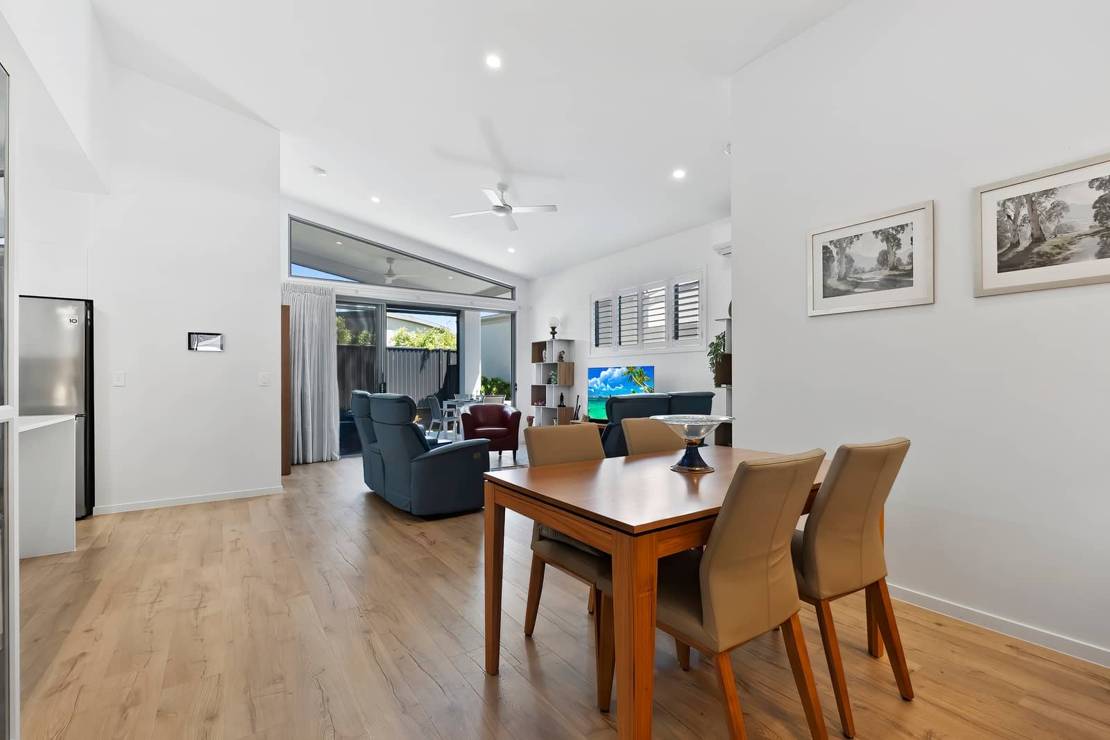 An open plan living and dining area in an Ingenia Lifestyle home, featuring a dining table, lounge, and glass doors to a patio.