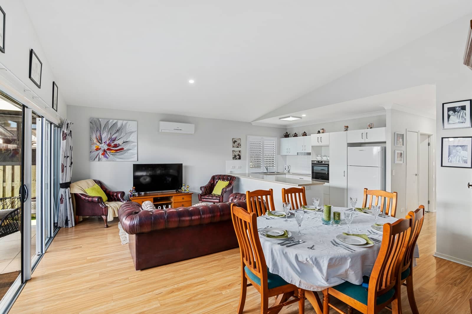 Dining and living area with a table set for a meal, leather sofa, and kitchen in an Ingenia Lifestyle home.