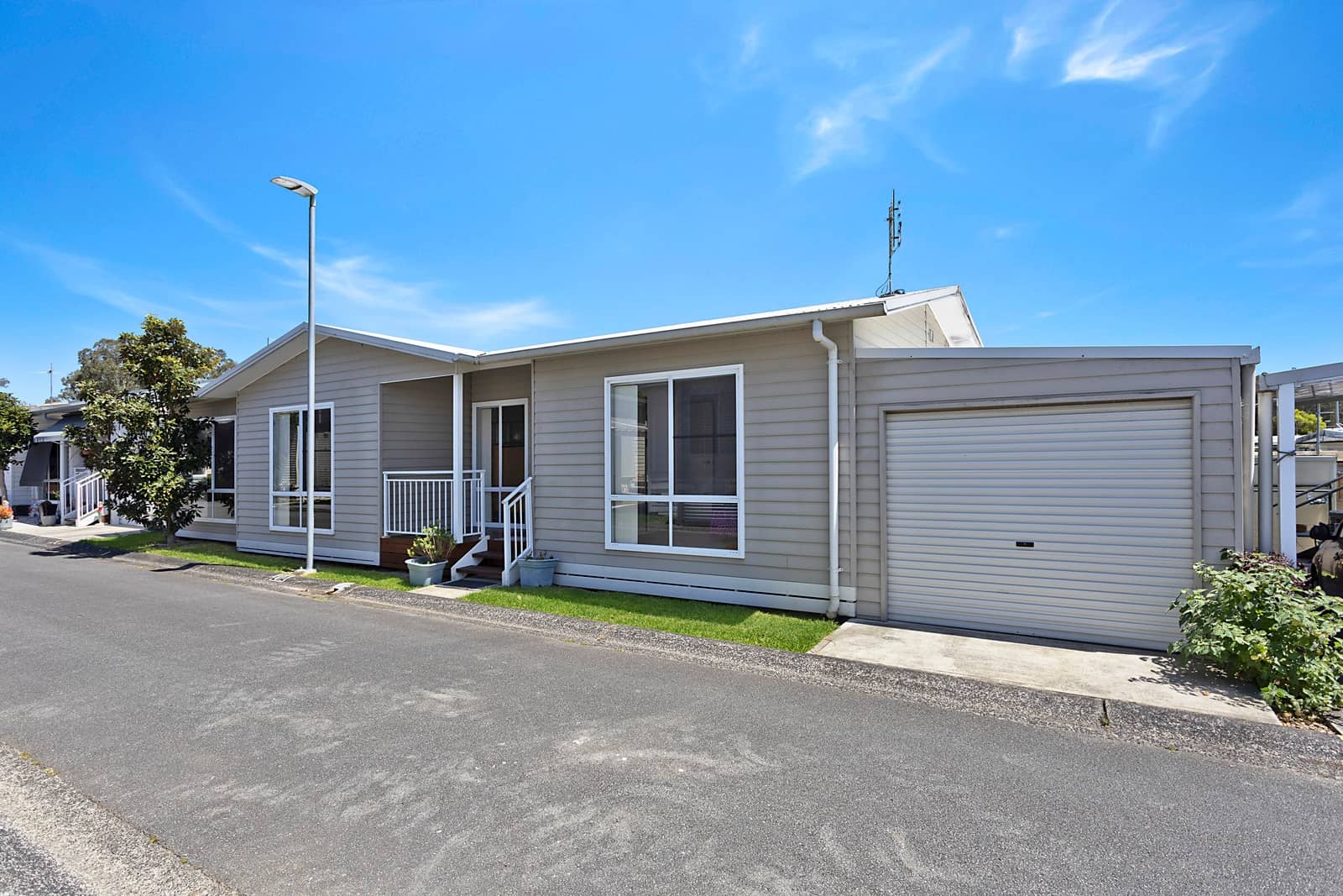 A modern grey land lease home with an attached garage and front porch in an Ingenia Lifestyle residential community.