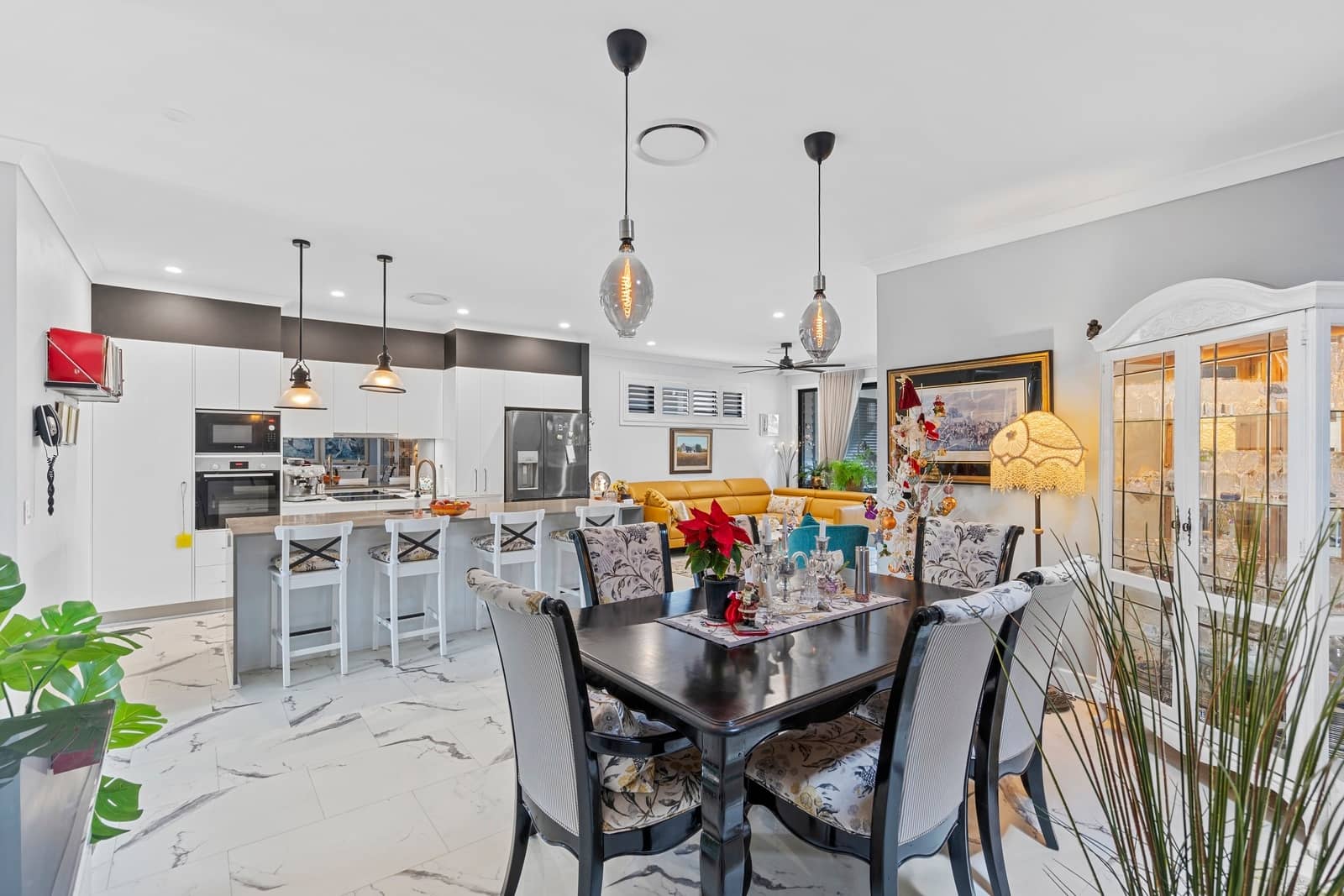 A dining area and open-plan kitchen in an Ingenia Lifestyle community home, featuring a dark wood table with upholstered chairs.