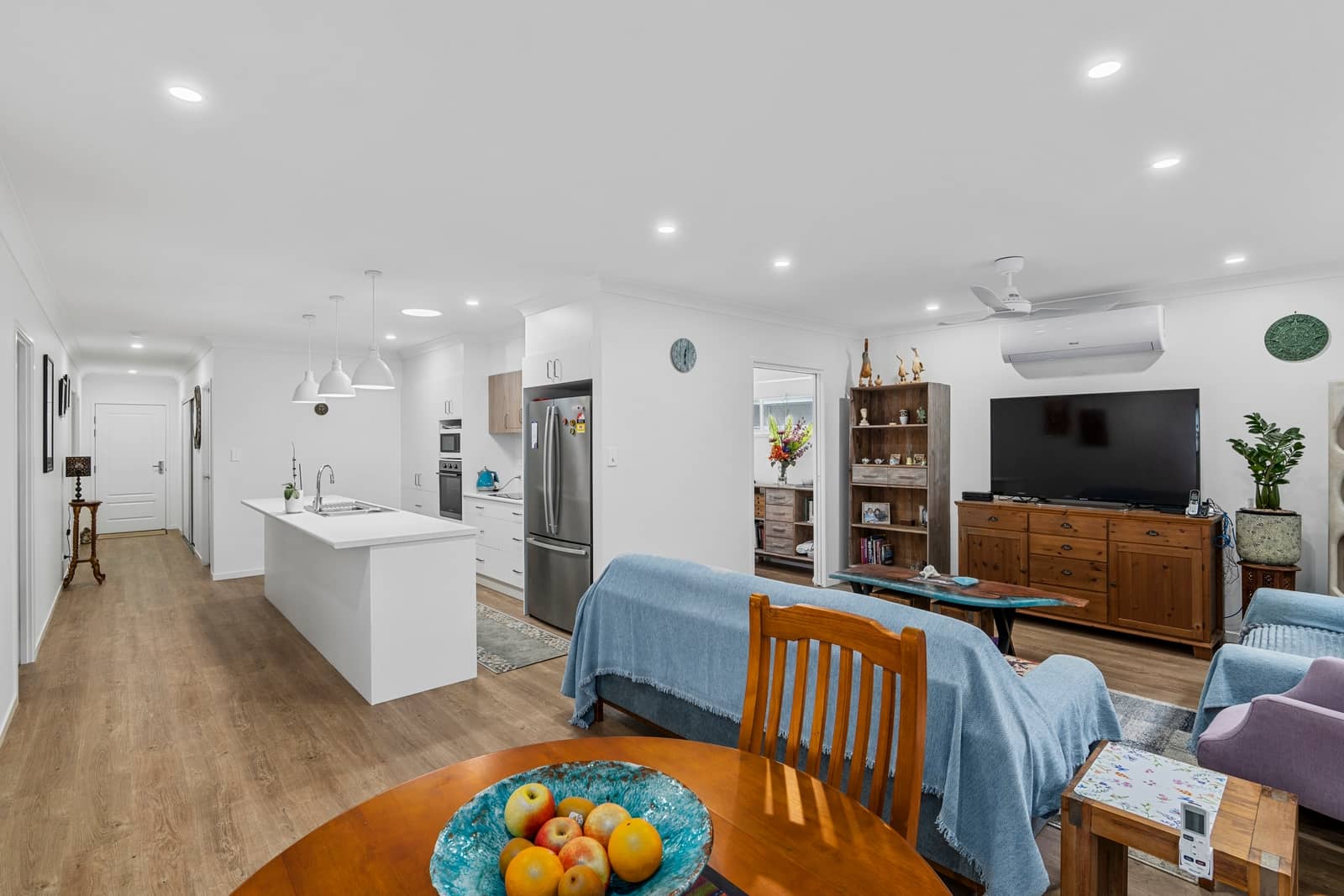 Open-plan living, dining, and modern kitchen with an island bench in an Ingenia Lifestyle home. Wood-look flooring.