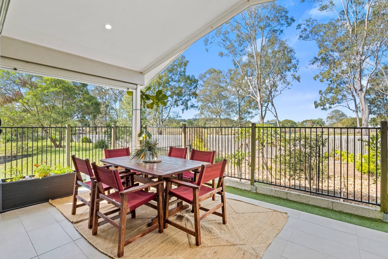 Covered outdoor patio of an Ingenia Lifestyle home, with a dining table, chairs, and a fenced garden view.