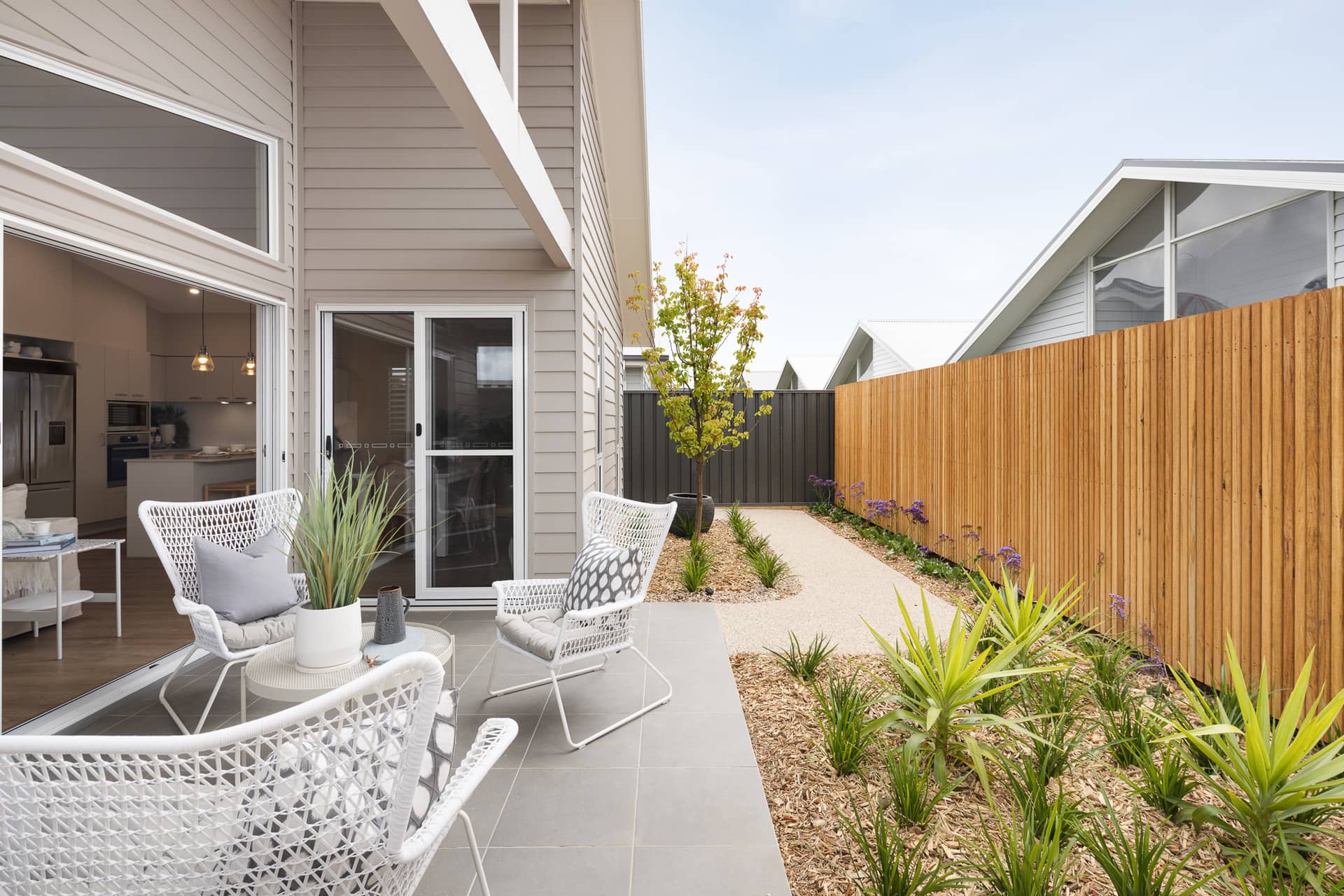 Patio with white wicker chairs and a table next to a land lease home in an Ingenia Lifestyle community.