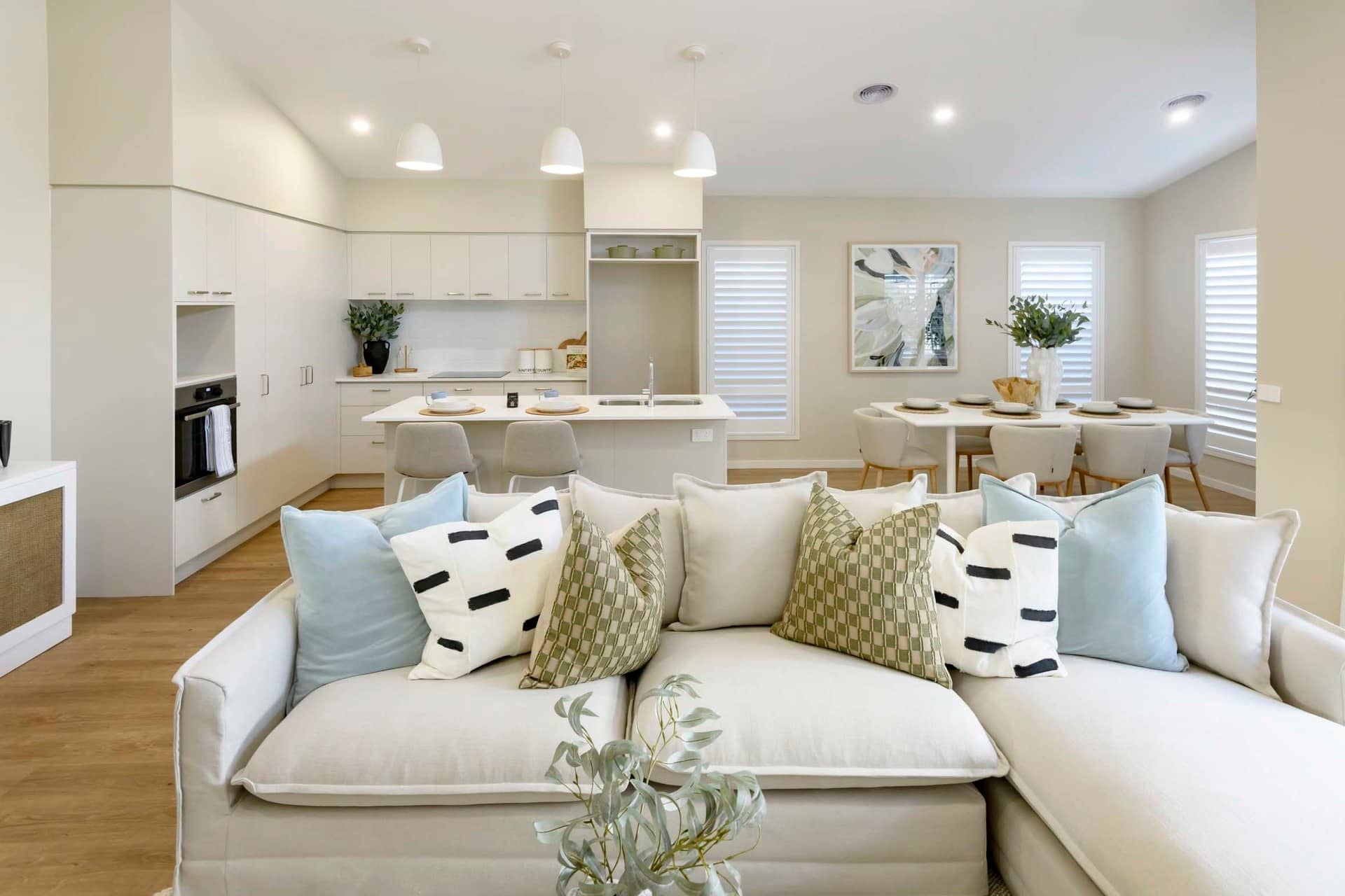 Modern living room and kitchen area in an Ingenia Lifestyle community with a sectional sofa and dining set.