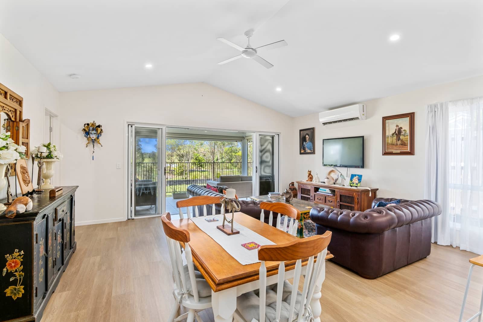 Interior view of a dining and living area with a patio overlooking landscaped grounds.