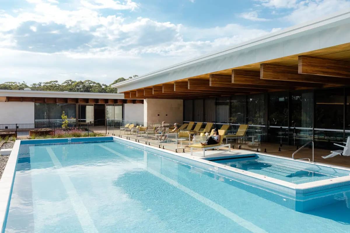 Residents relaxing on sun loungers by the swimming pool and spa at an Ingenia Lifestyle community’s shared amenities.