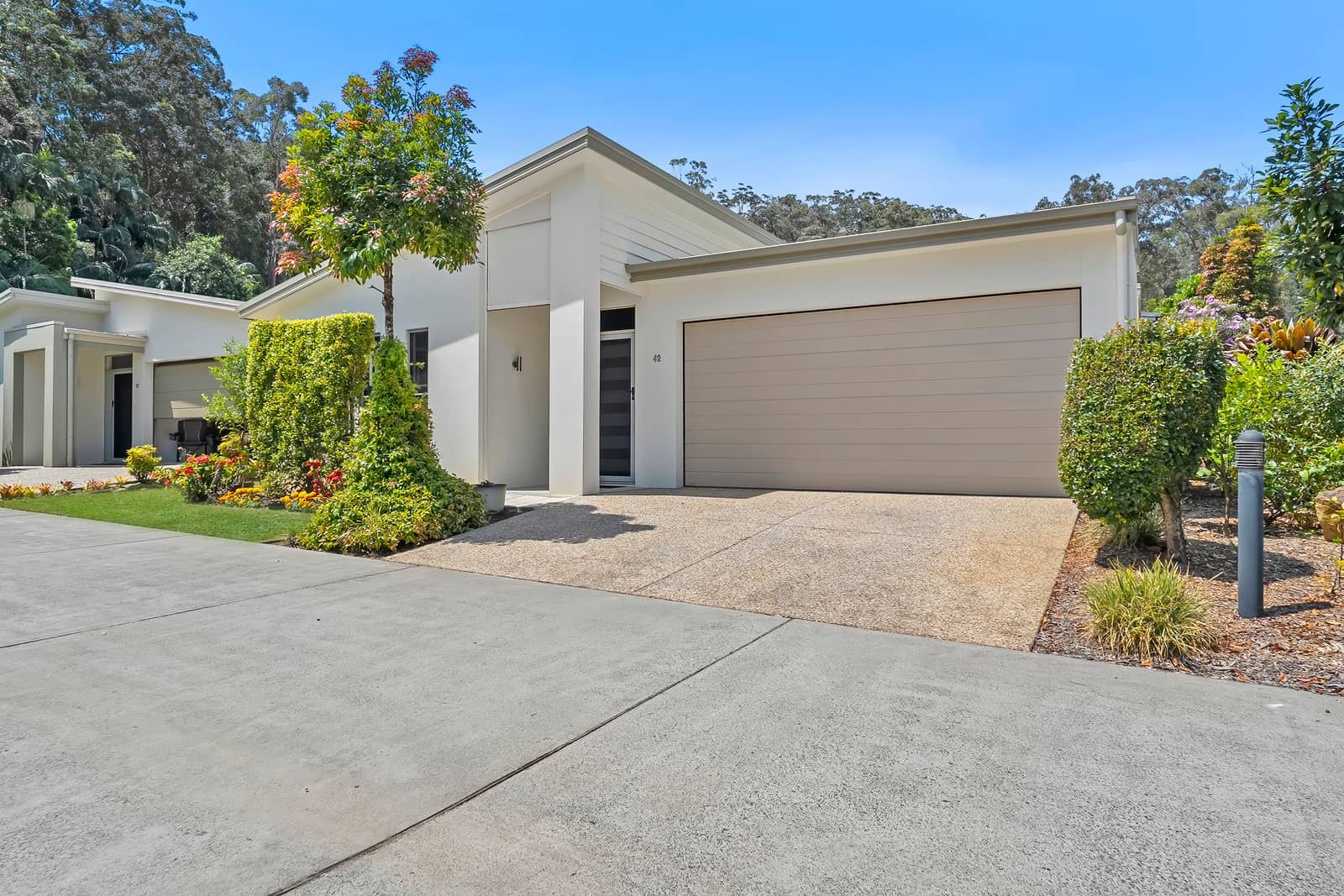 Exterior of modern land-lease homes with attached garages and lush, landscaped grounds in an Ingenia Lifestyle community.
