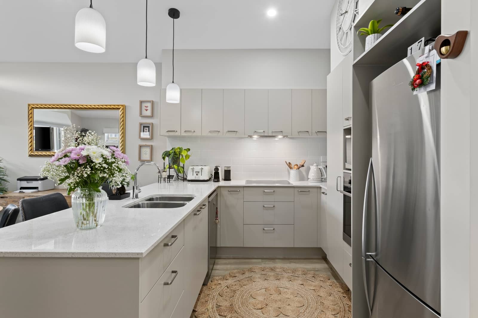 Modern kitchen in an Ingenia Lifestyle community with neutral cabinetry, stainless steel appliances, and a floral arrangement.