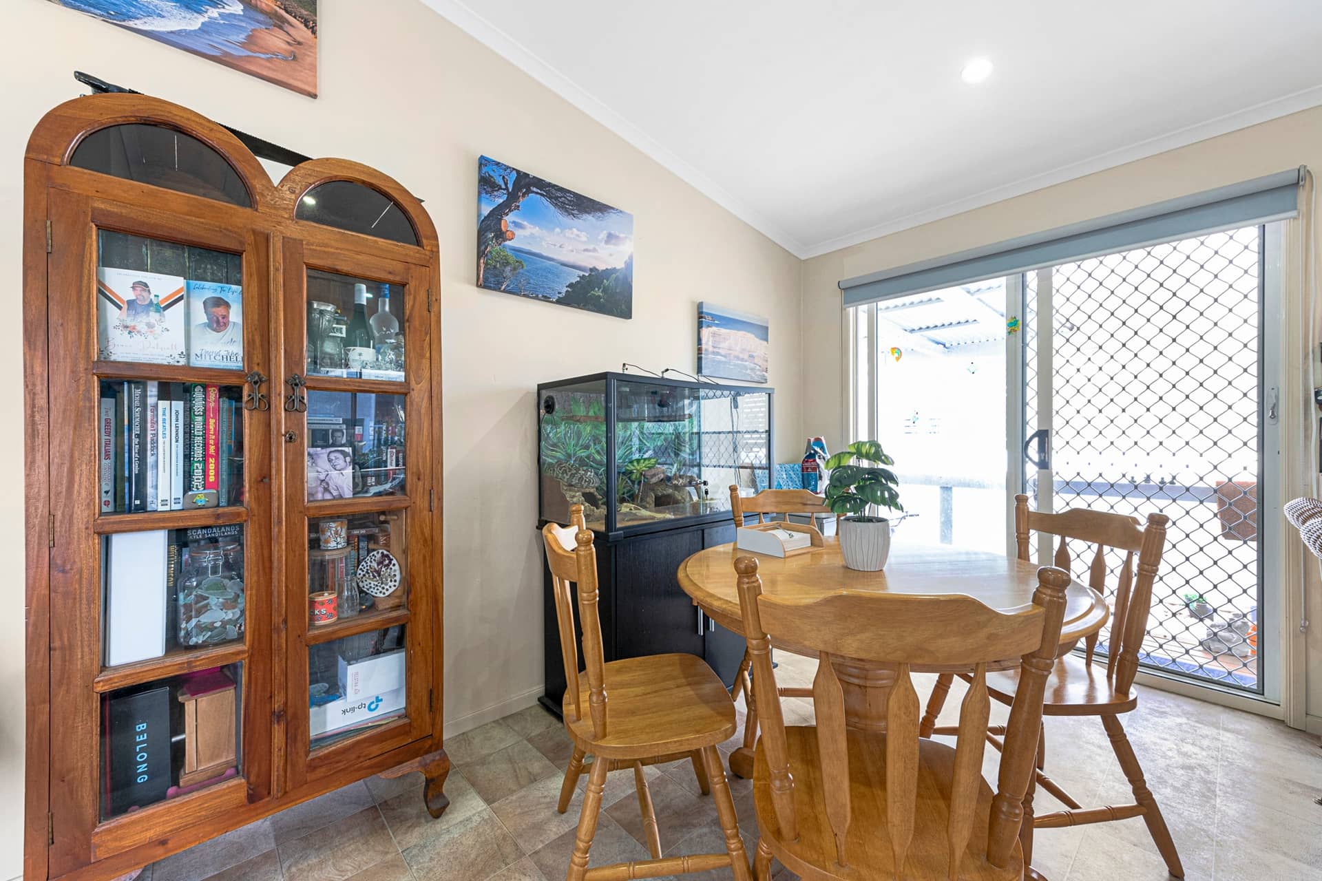 Dining area in an Ingenia Lifestyle home with a wooden table, chairs, a display cabinet, and a terrarium. Sliding door to patio.
