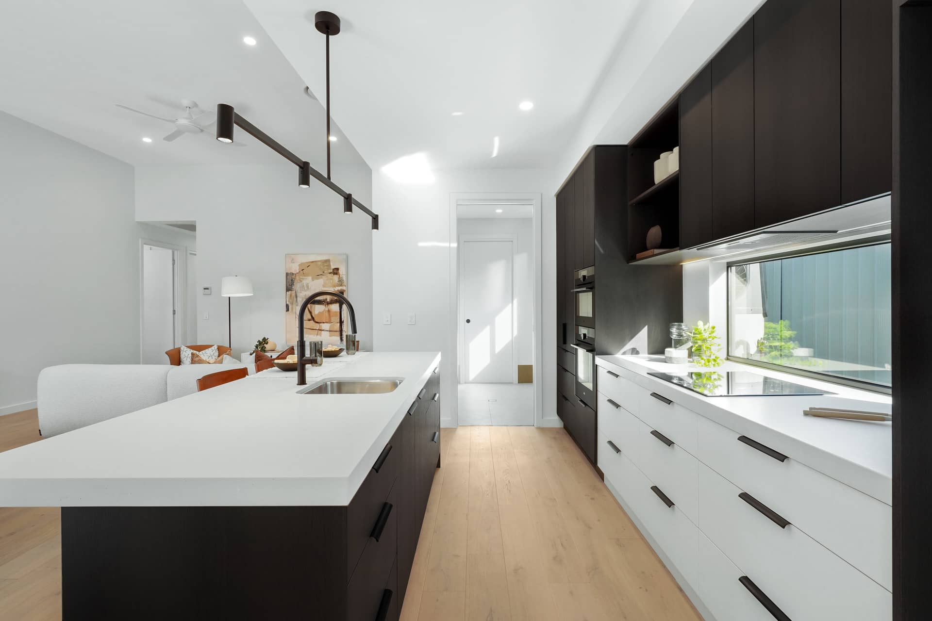 Modern kitchen with island bench, dark wood cabinetry, and white benchtops in an Ingenia Lifestyle community.
