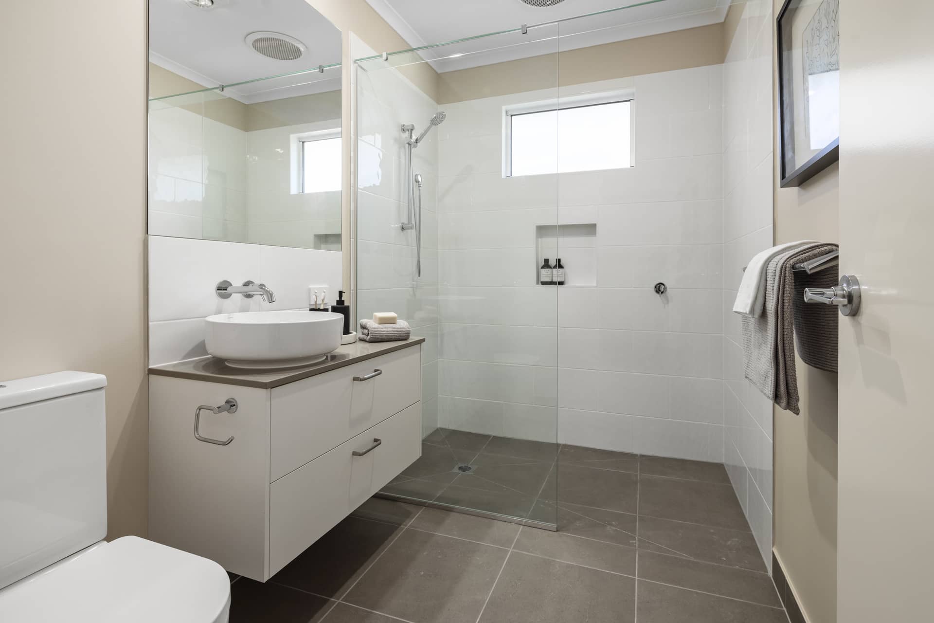 Modern bathroom with white vanity, vessel sink, glass-enclosed shower, and toilet.