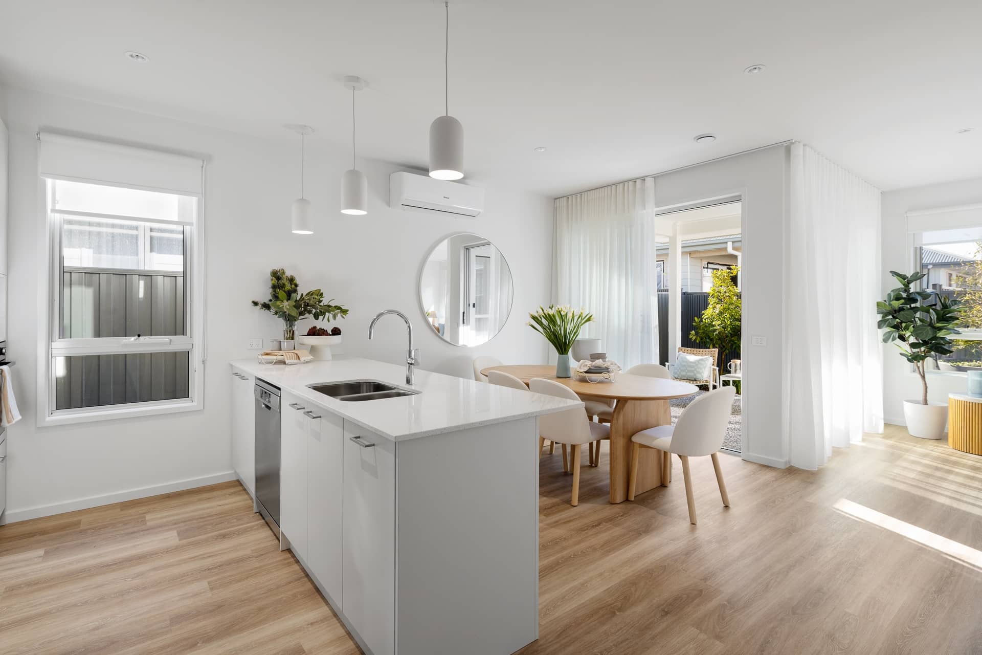 Ingenia Lifestyle home's bright, open-plan kitchen and dining area with white island, timber floors, and patio access.