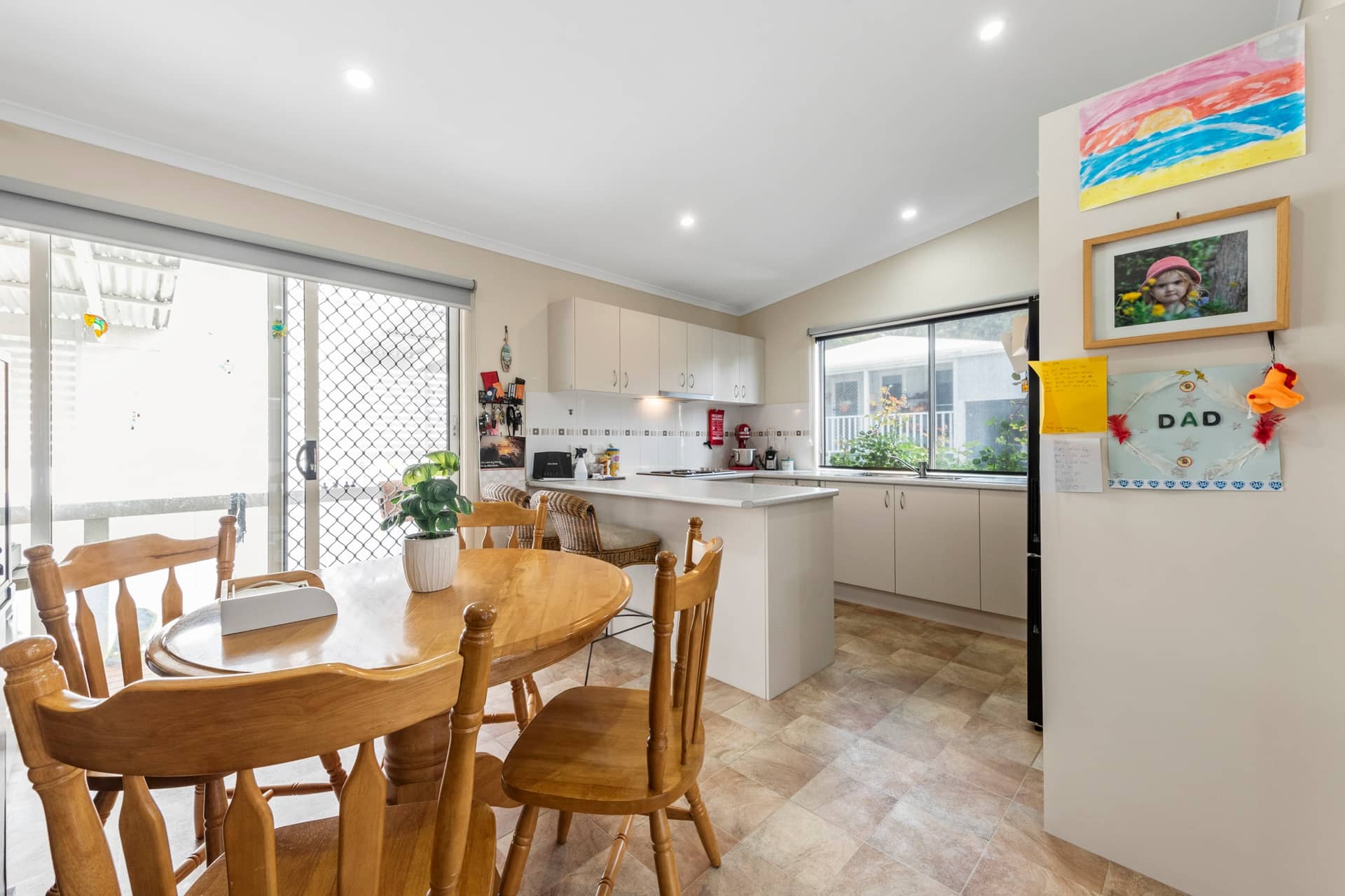 An open-plan kitchen and dining area in an Ingenia Lifestyle home, with a wooden table, light cabinetry, and an island bench.