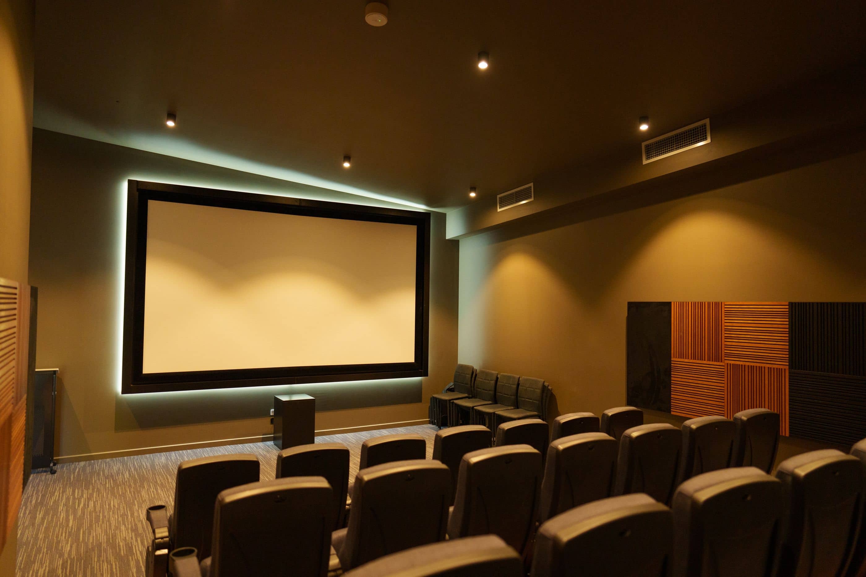 Cinema room amenity in an Ingenia Lifestyle community, with a large screen, rows of dark seating, and acoustic panels.