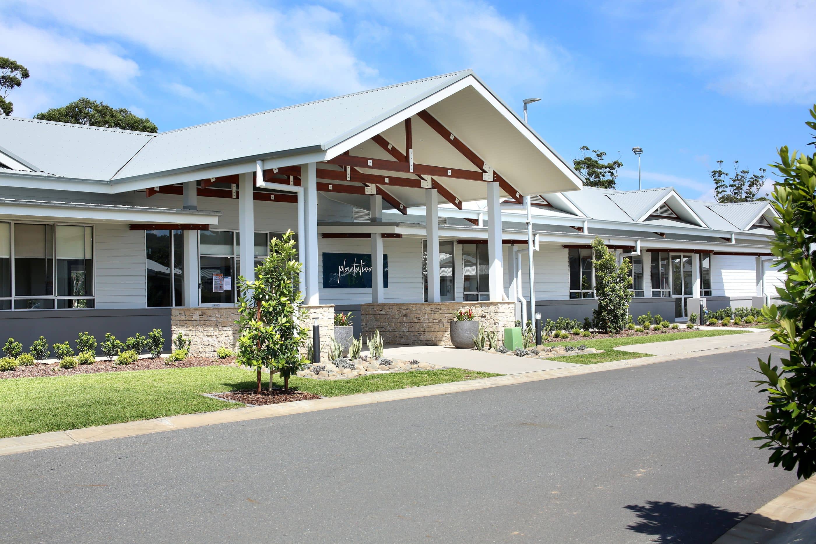 A modern community building with a metal roof and stone accents, set against a blue sky.