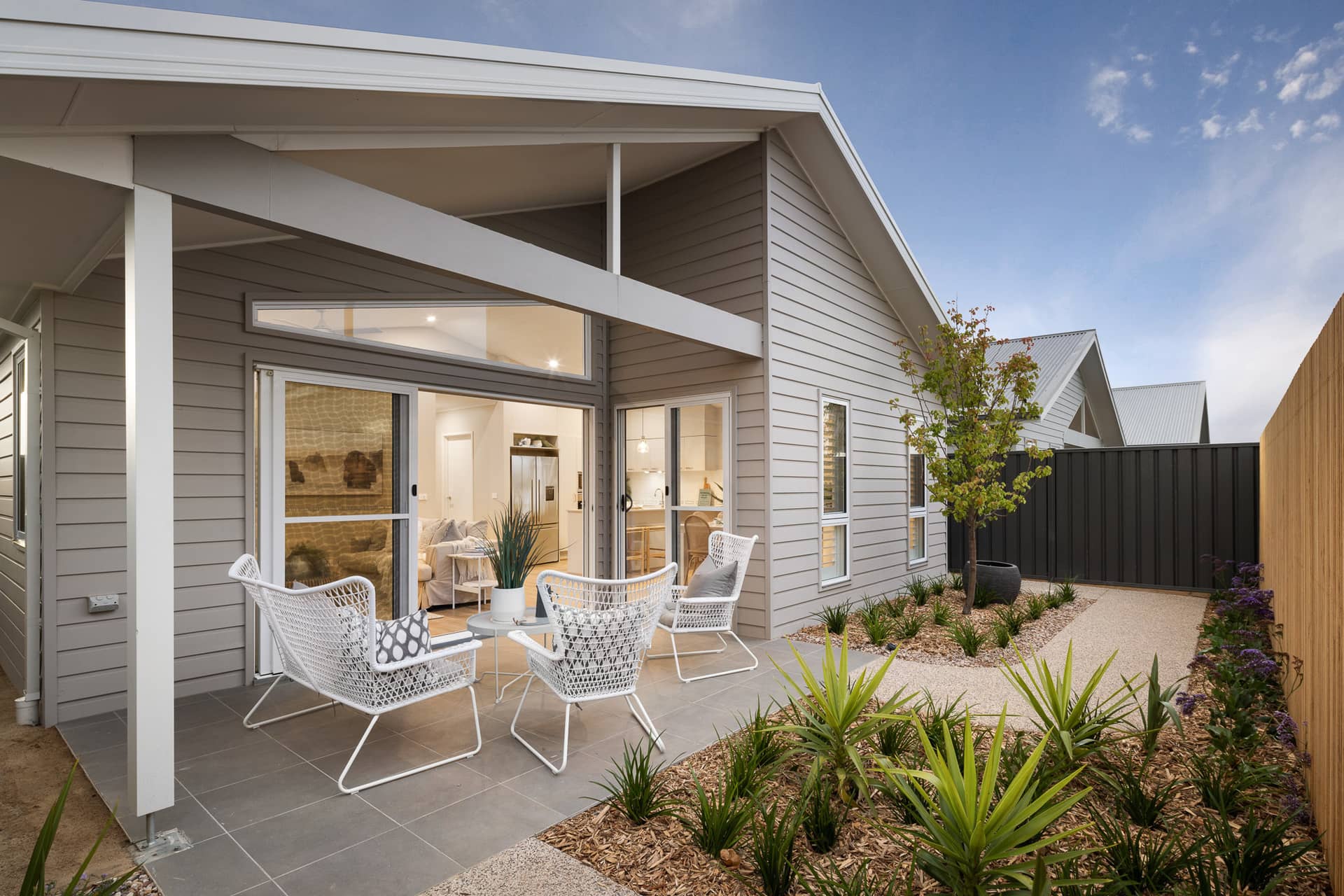A modern land lease home with an outdoor patio featuring white chairs and a small table.