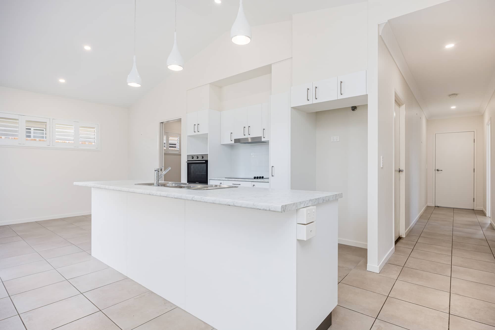 Modern white kitchen with island bench and stainless steel appliances in Ingenia Lifestyle community.