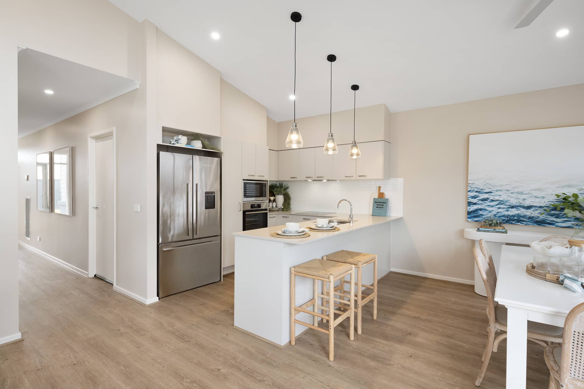 Modern kitchen and dining area in an Ingenia Lifestyle community home with island bench, stainless steel fridge, and dining setting.