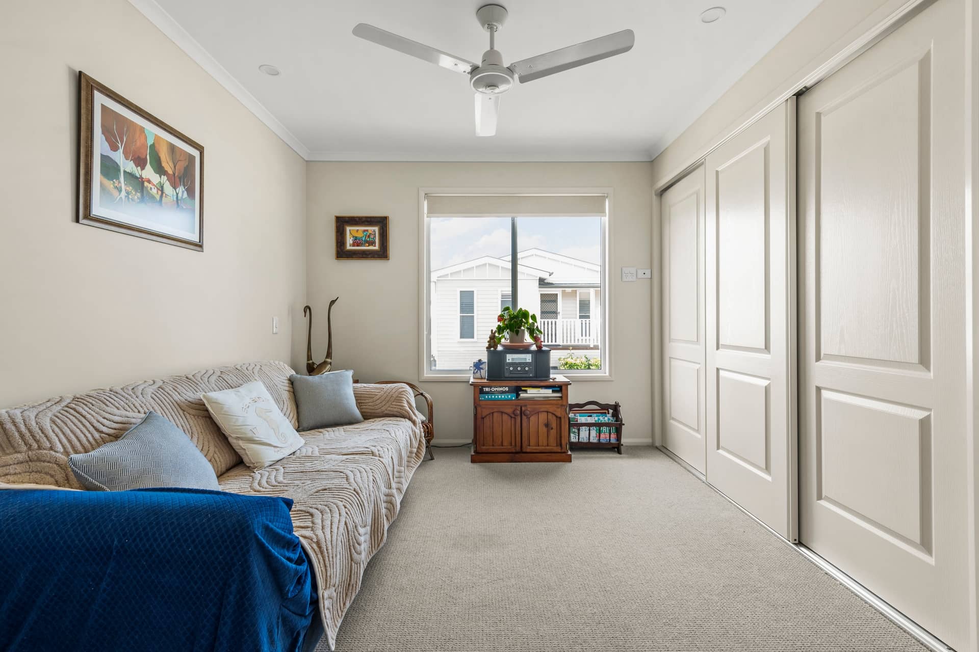 Ingenia Lifestyle home interior with sofa, window to community, ceiling fan, and built-in sliding wardrobes.