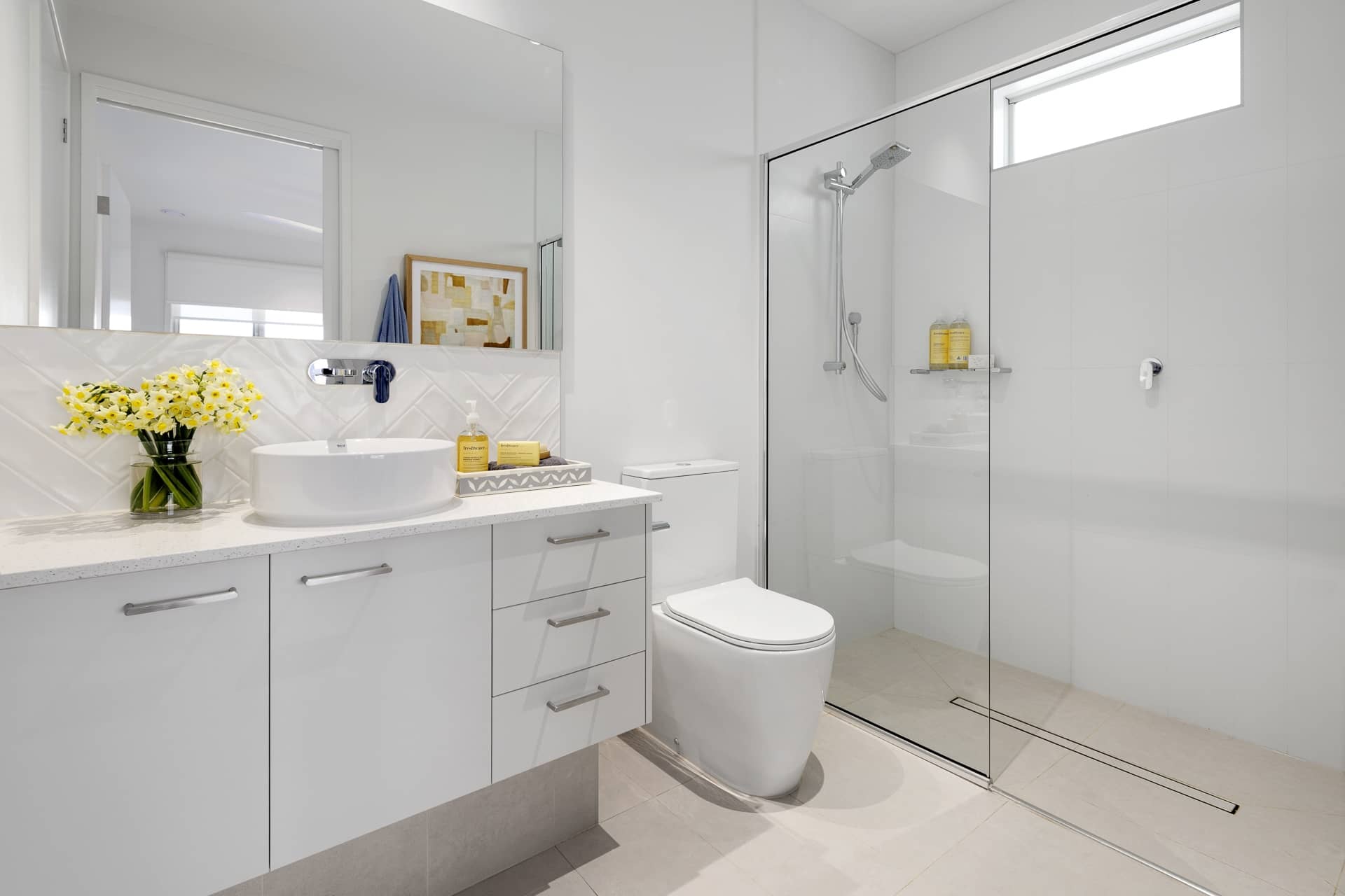 A contemporary bathroom in an Ingenia Lifestyle home featuring a white vanity with basin, glass shower, and toilet.